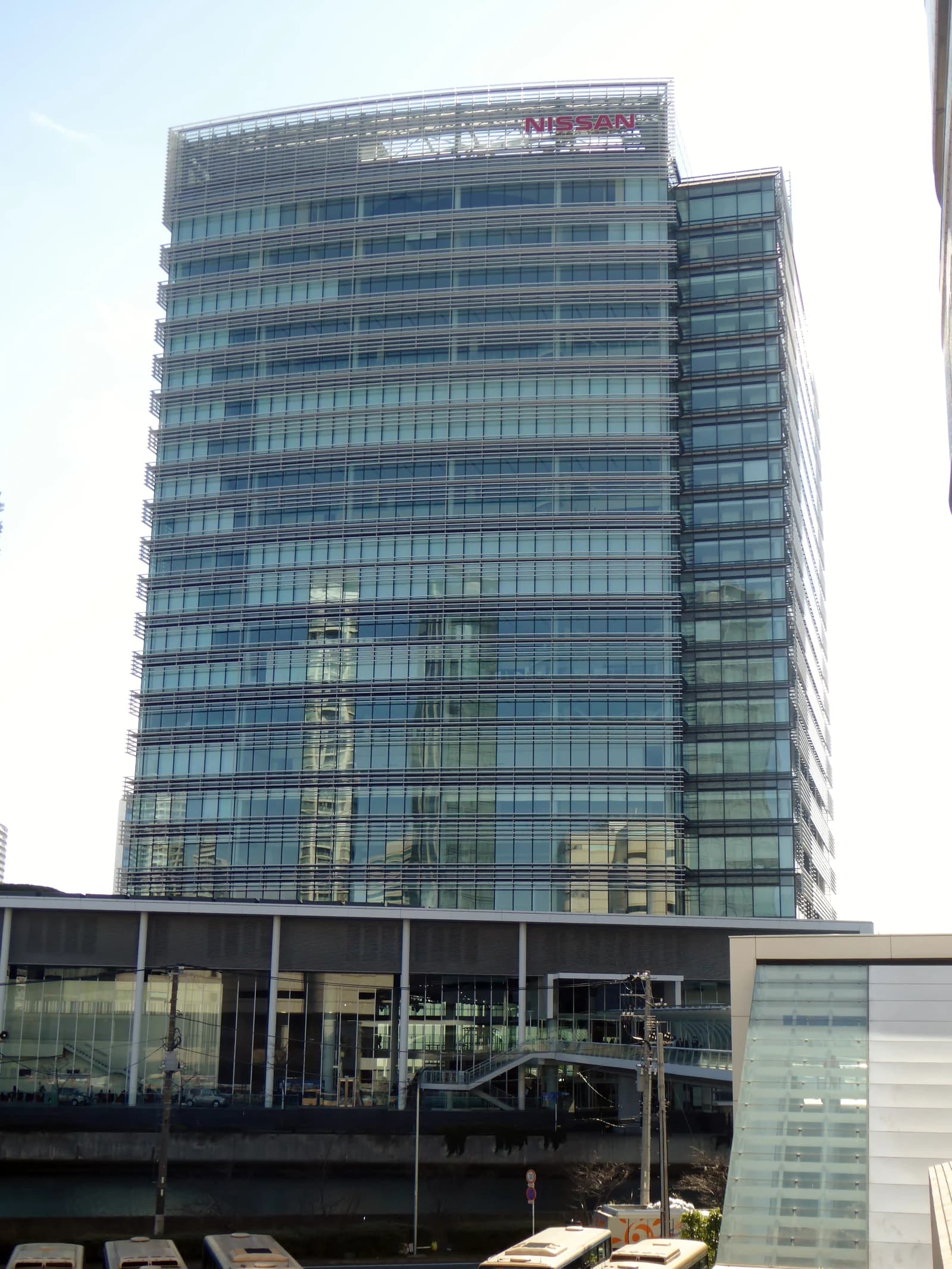 Nissan Motor Co. headquarters, a large glass and steel building, against a clear sky.