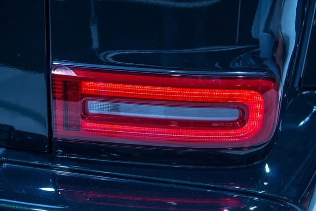 Illuminated taillight of a dark Mercedes-Benz G-Class on display.