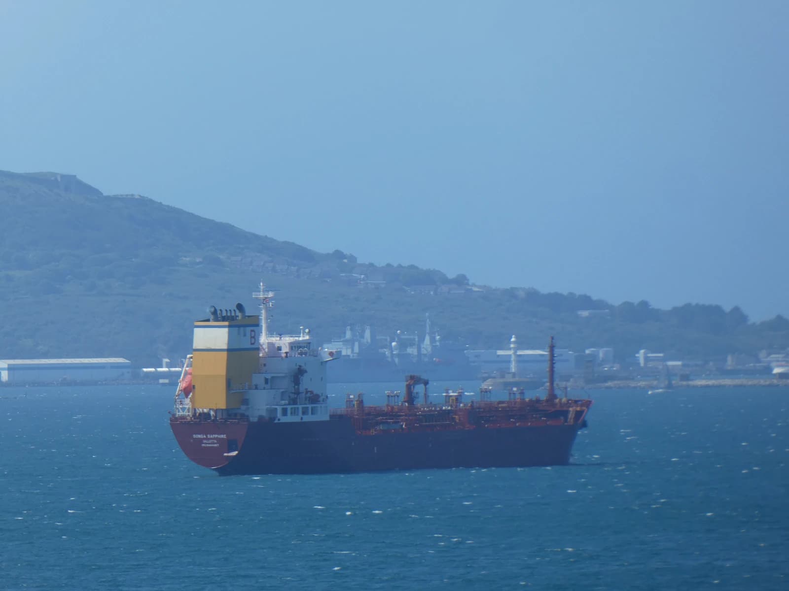 Oil tanker Songa Sapphire in open water near a hilly coastline.