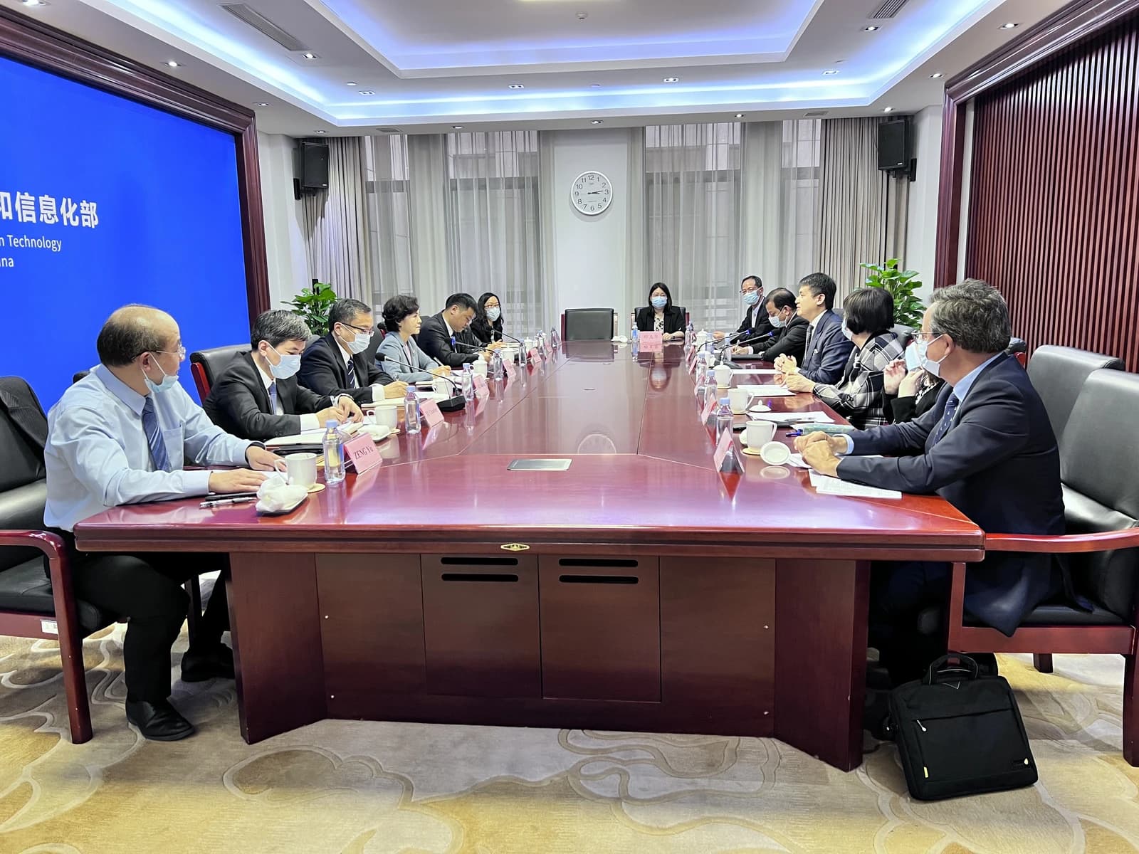 Group of officials attending a meeting at a long conference table.
