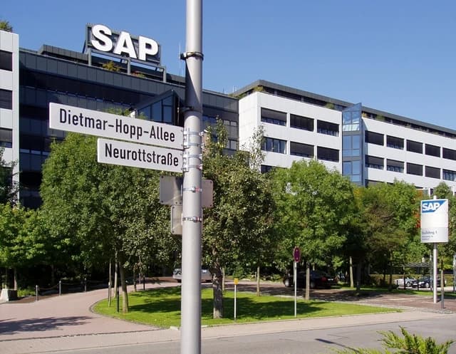 Exterior view of the SAP AG headquarters building with street signs in front.