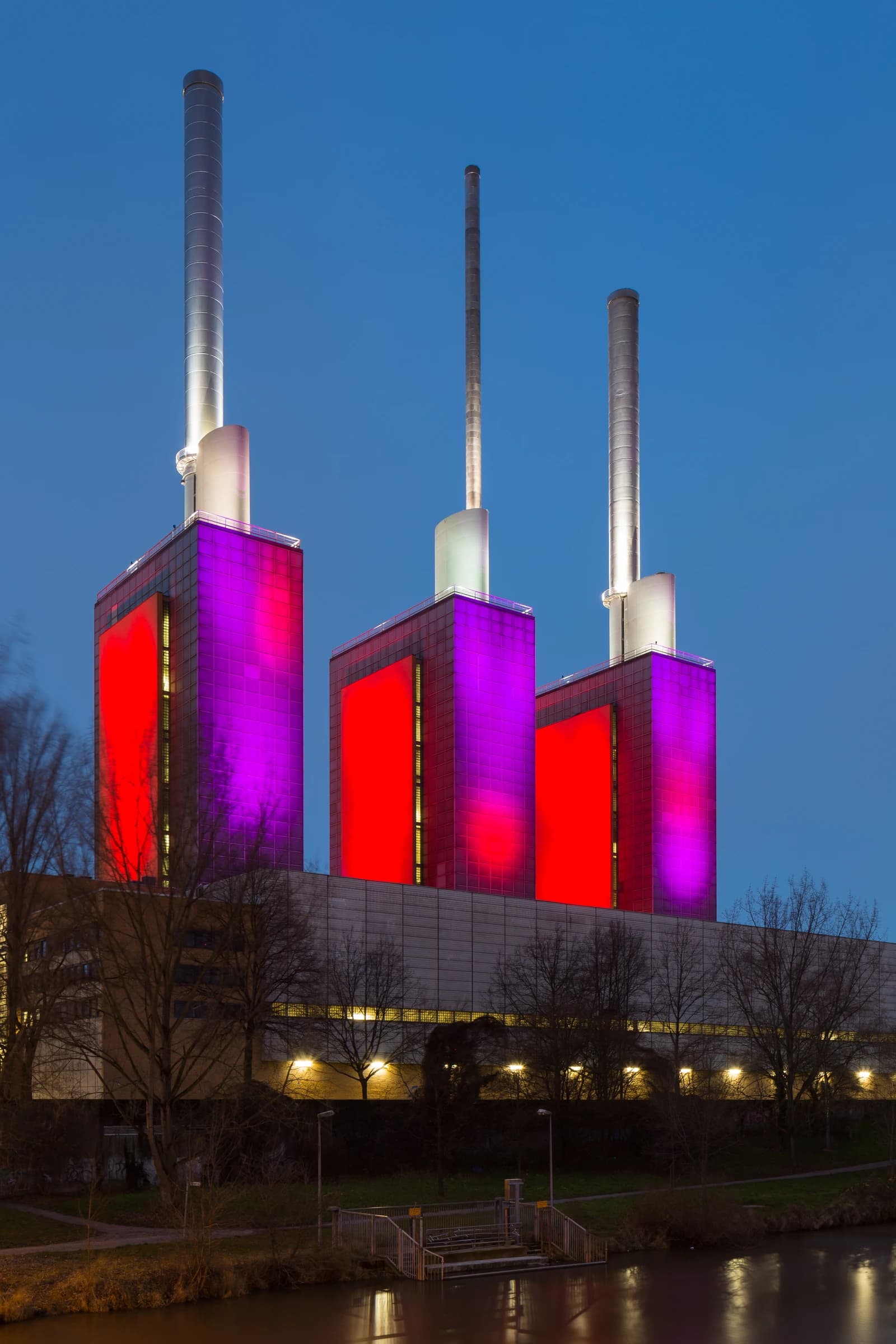 Linden power plant with three tall chimneys and illuminated red and purple towers.