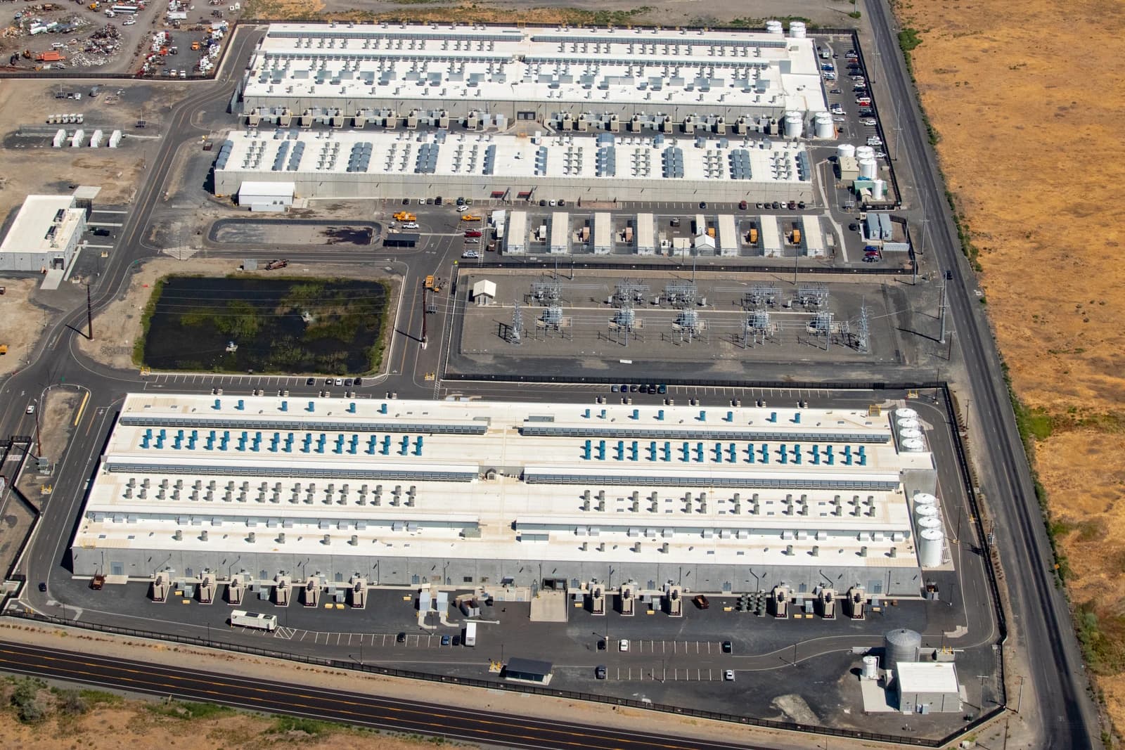 Aerial view of Amazon Web Services data center campus, with multiple large buildings.