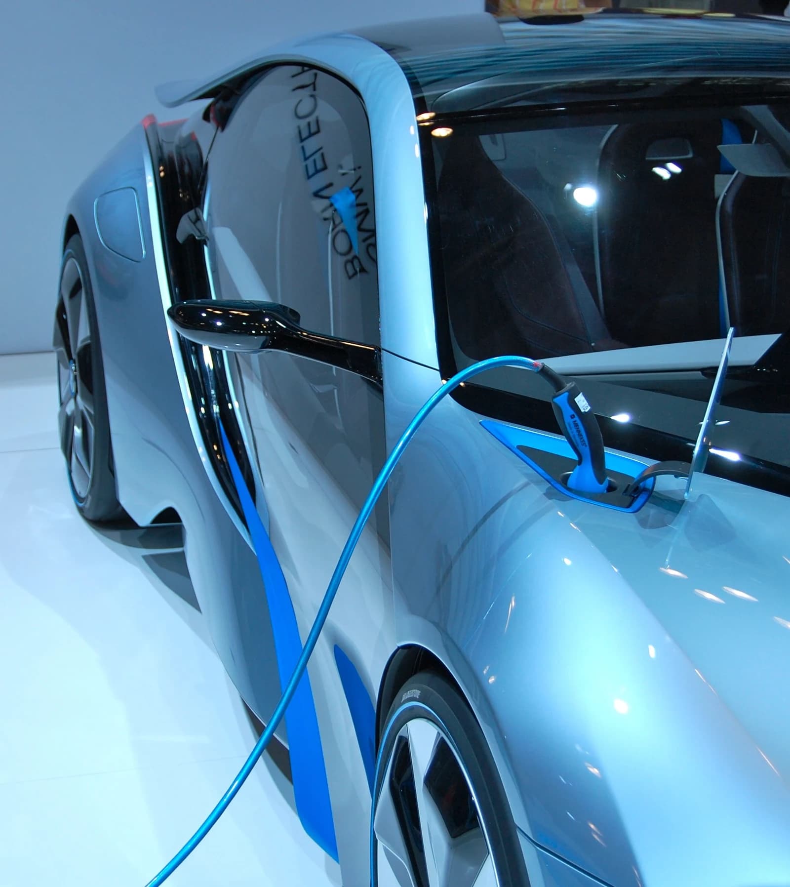 Close-up of a silver BMW electric car being charged at a station.