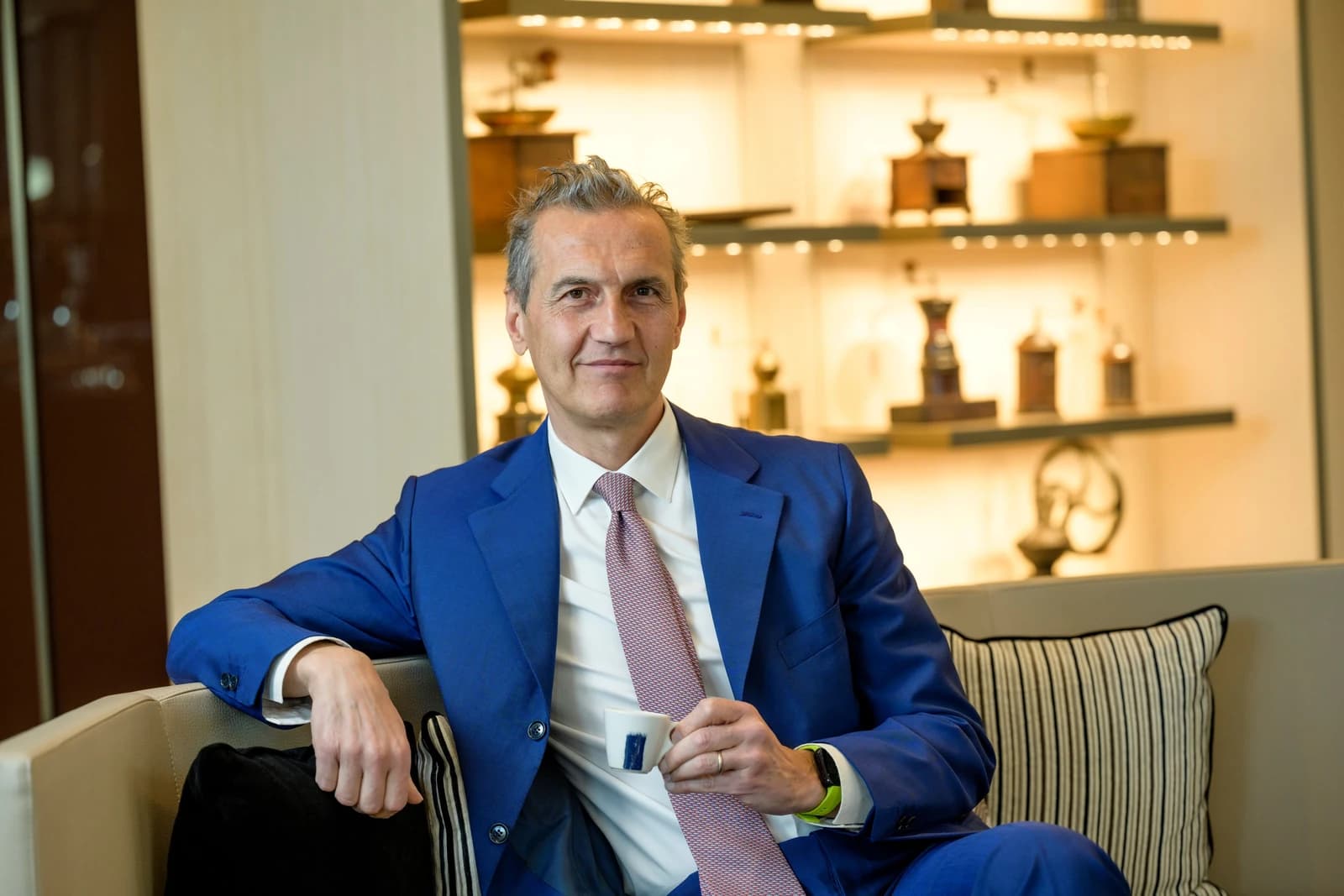 Antonio Baravalle, CEO of Lavazza Group, sitting on a sofa and holding a small coffee cup.