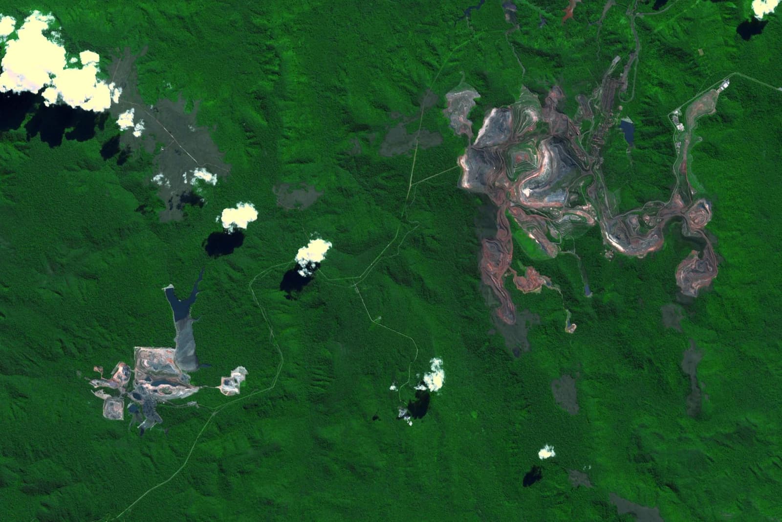 Satellite view showing the large Carajás iron ore mine in Brazil amidst lush green forest.