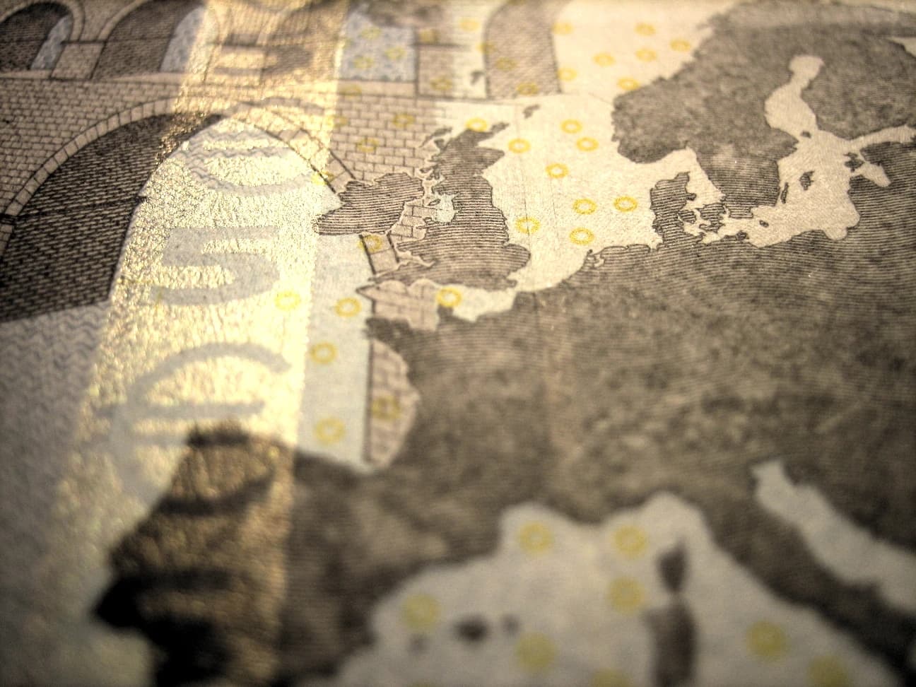 Close-up of a euro banknote depicting a bridge and the map of Europe.