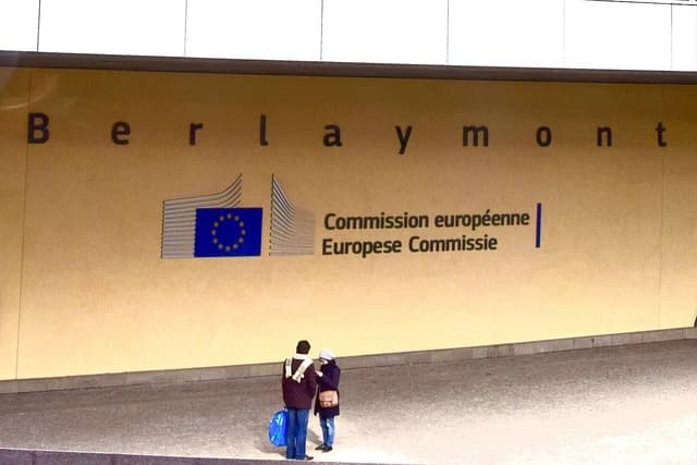The European Commission headquarters building in Brussels, Belgium, with people standing outside.