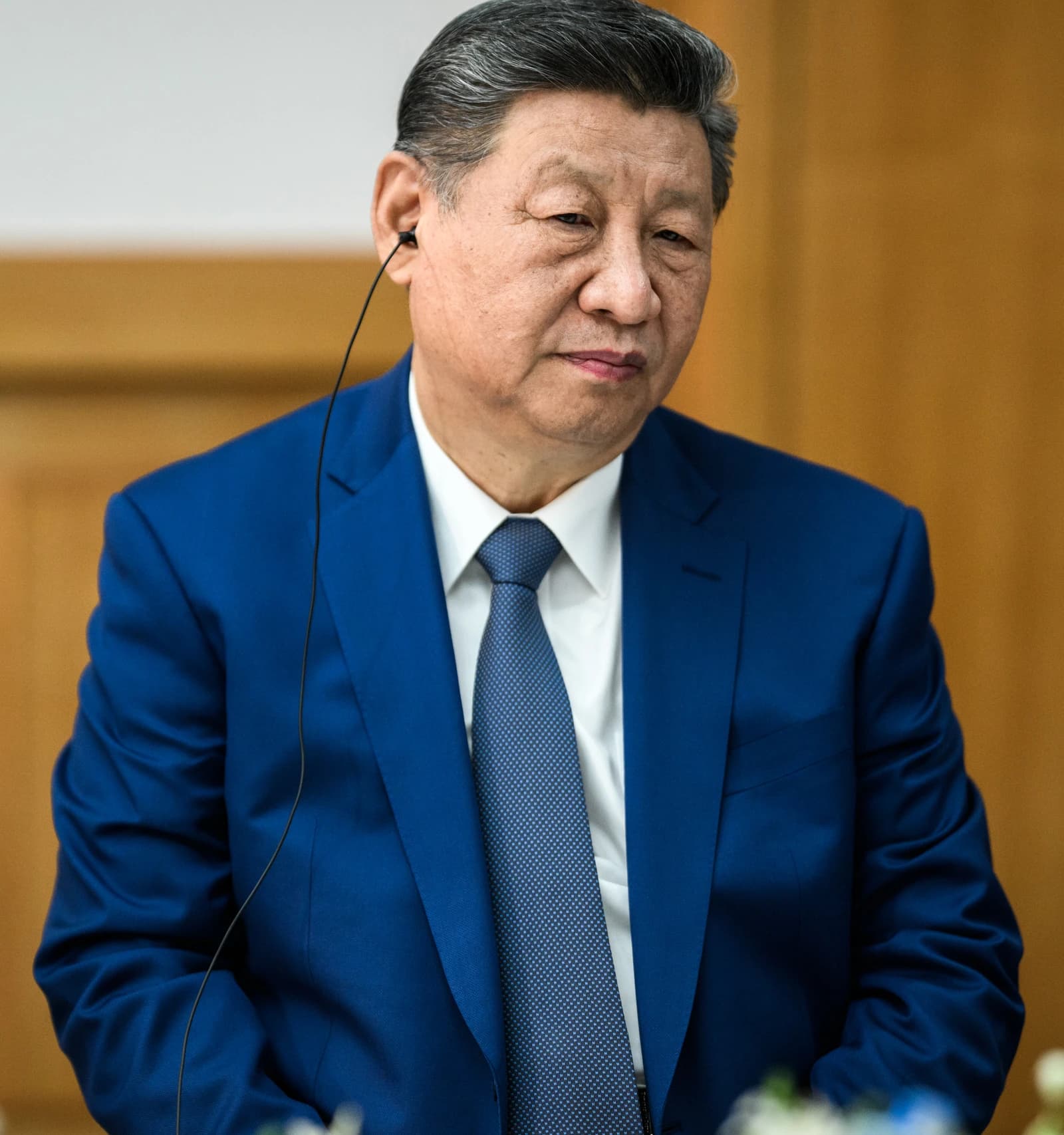 Chinese President Xi Jinping listening with an earpiece during an event.