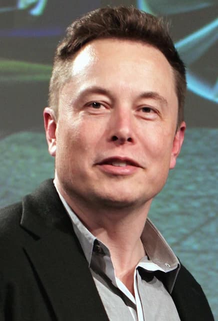 Elon Musk, CEO of Tesla, looking towards the camera at an event.