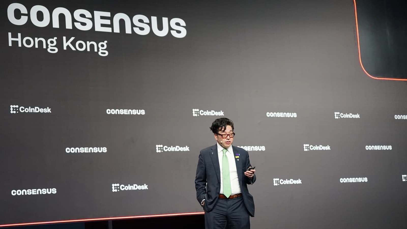 Tom Lee speaking at the Consensus Hong Kong conference in front of a branded wall.