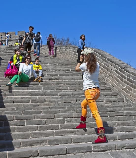 Chinese tourists pose for photos and climb steps on the Great Wall of China.