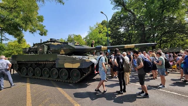 A Hungarian Leopard 2A7HU tank on display outdoors with people observing it.