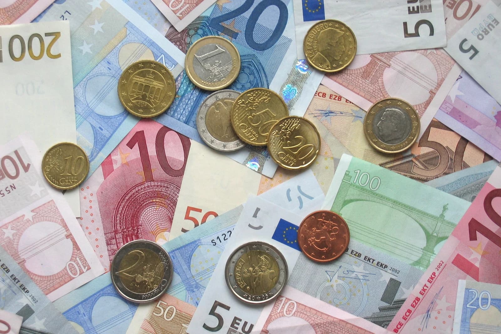 Close-up of various Euro banknotes and coins lying together on a surface.