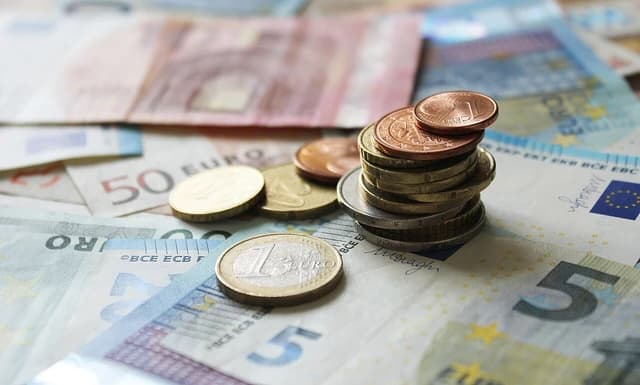 Euro banknotes and coins, including a stack of coins and a one-euro coin.