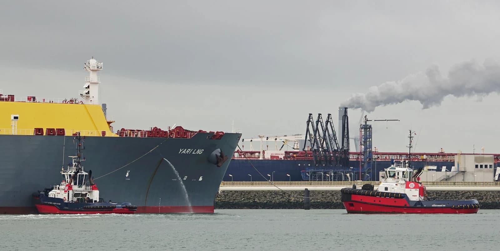 LNG tanker Yari LNG with tugboats near industrial facility in Rotterdam.