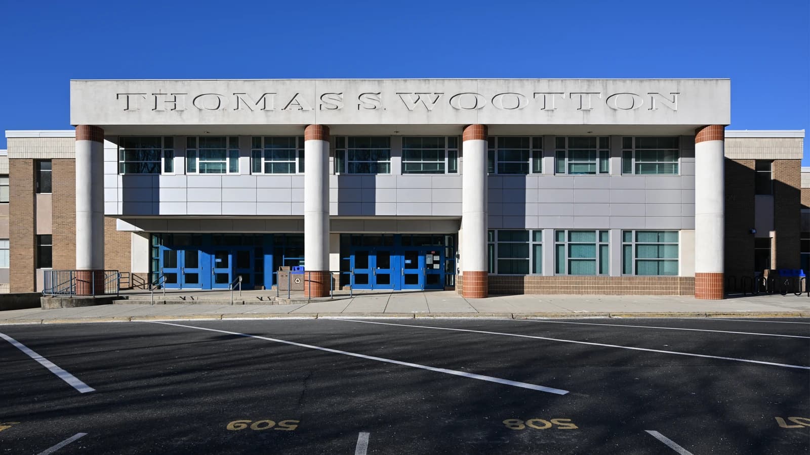 Thomas S. Wootton High School entrance with blue doors under a clear sky.