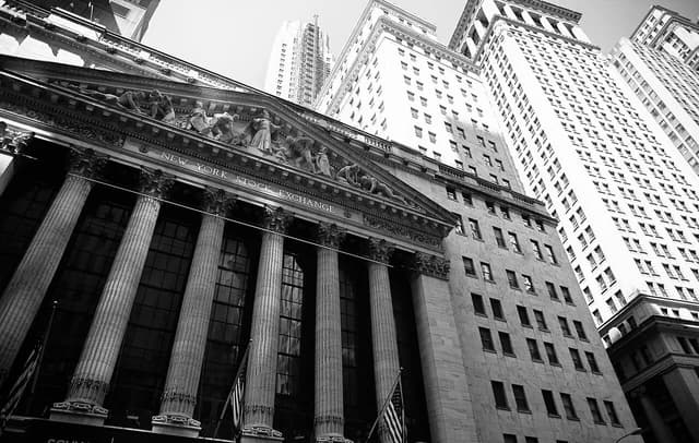 Exterior view of the New York Stock Exchange building in Manhattan, with surrounding skyscrapers.