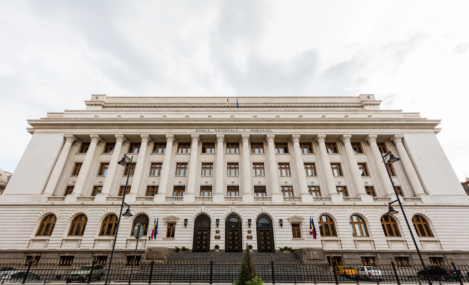 Exterior view of the National Bank of Romania building with columns and flags.