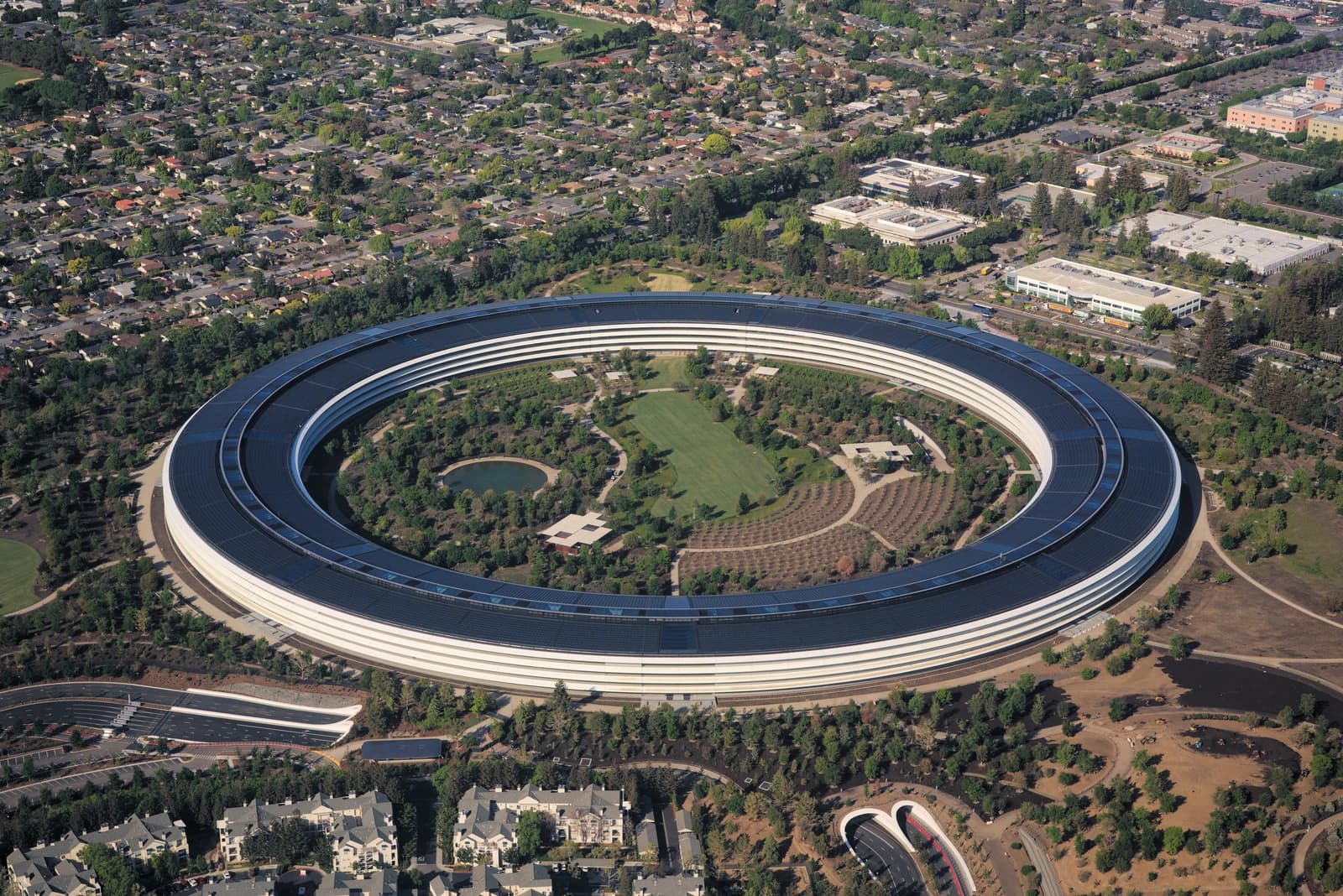 Aerial view of Apple Park in Cupertino, California, a large circular building surrounded by trees.