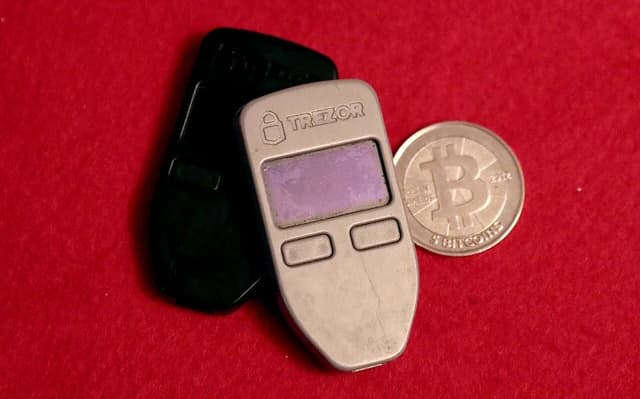 Two Trezor One hardware wallets and a Casascius physical Bitcoin coin.