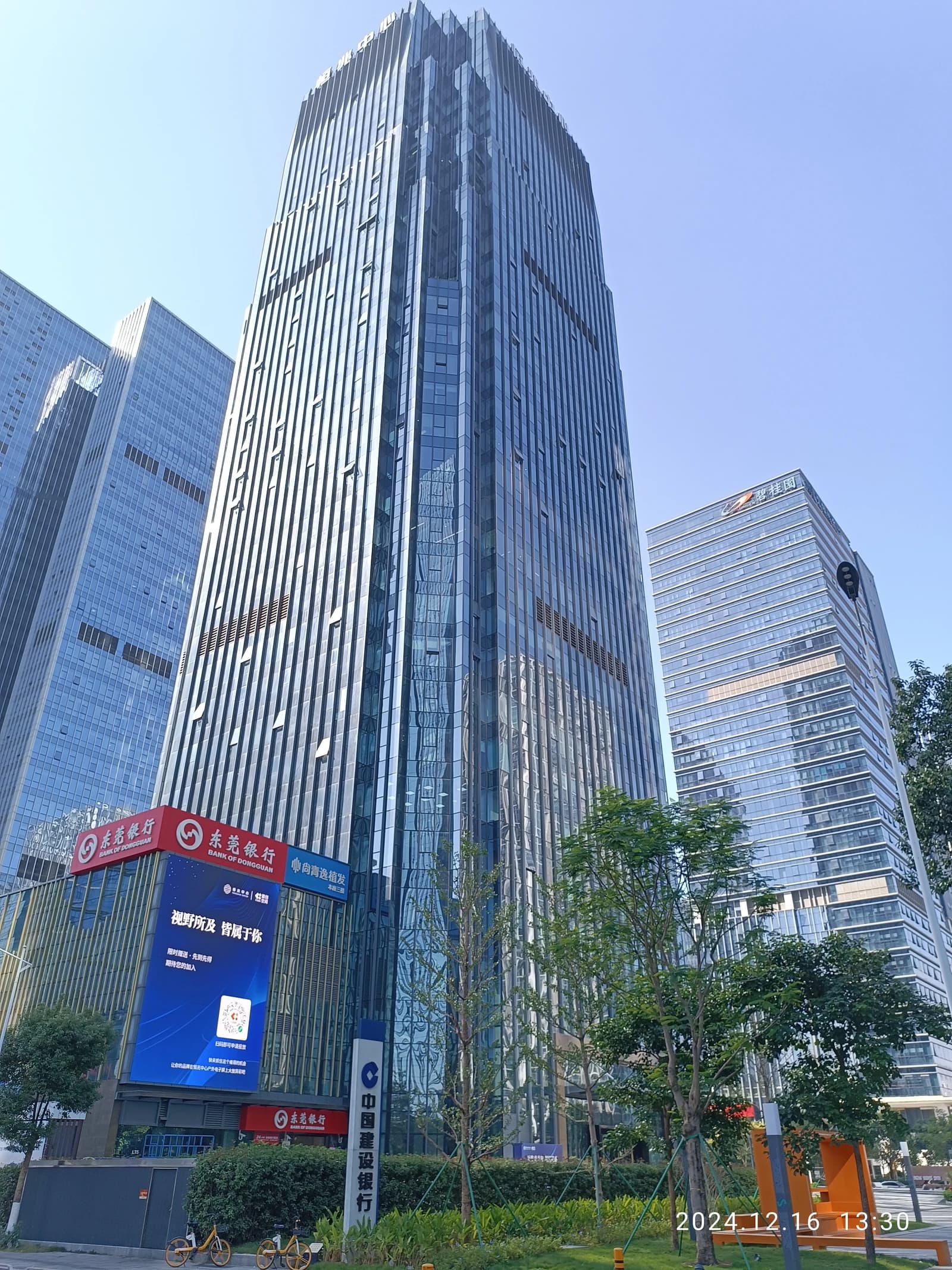 Modern glass-fronted office towers and street level signage in Dongguan, China.