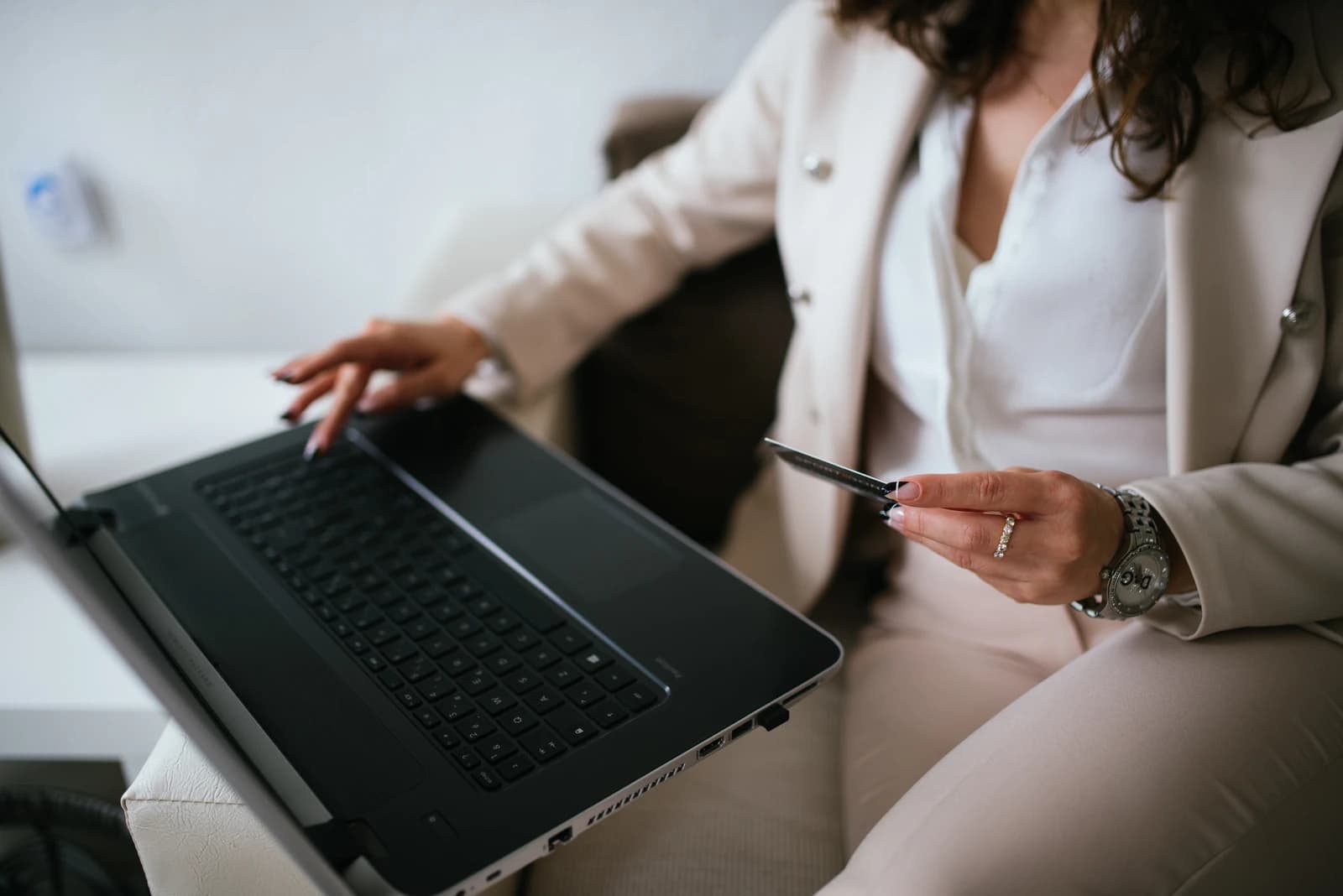 Business professional shops online at home workspace, holding a credit card.