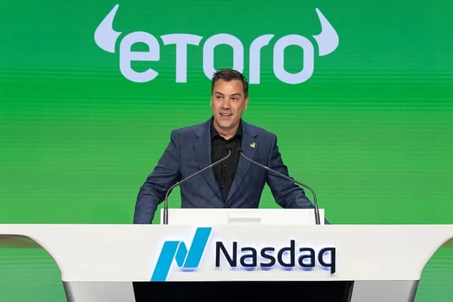 Yoni Assia, CEO of eToro, speaking at a podium at the Nasdaq stock exchange.
