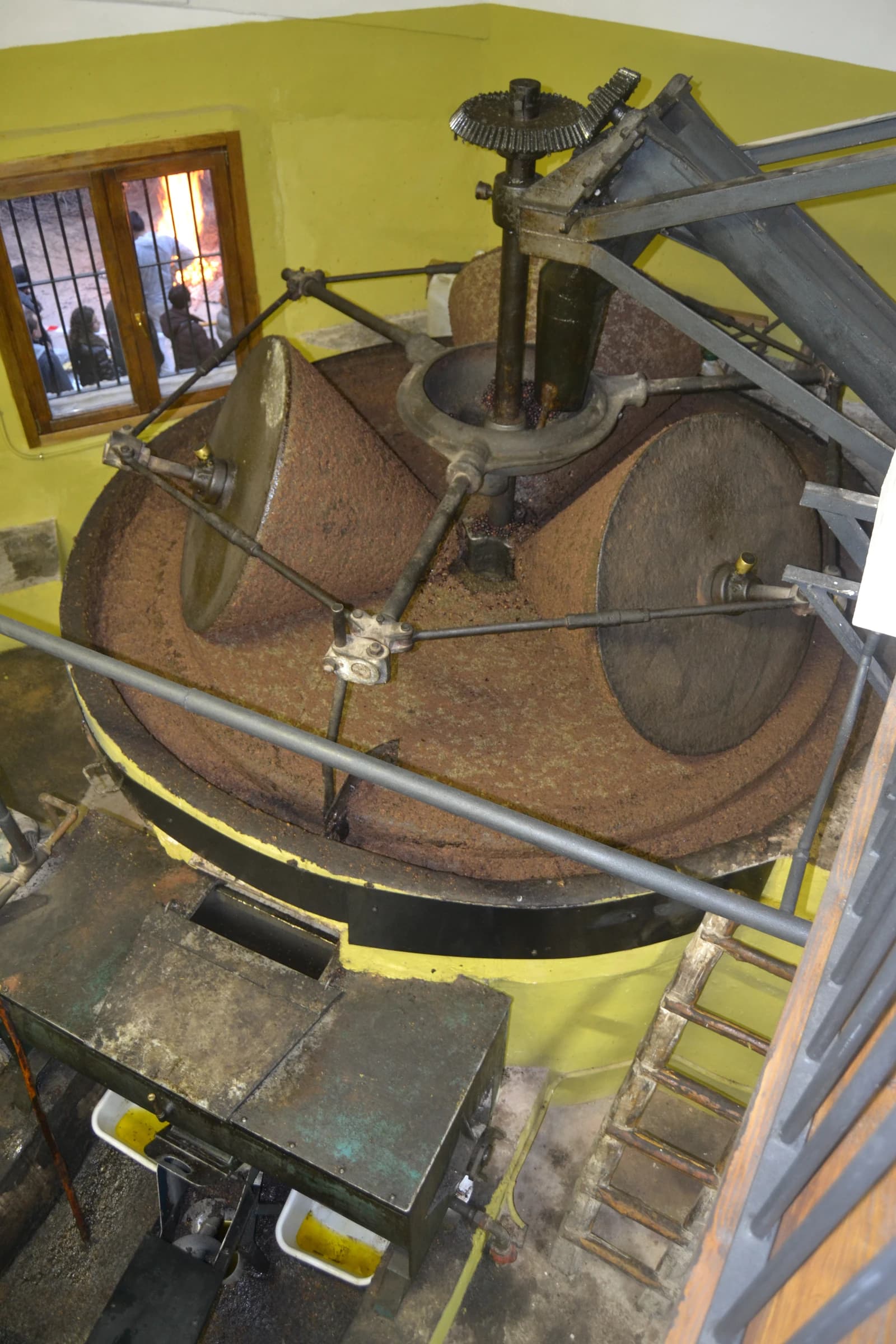 Traditional olive oil mill showing large grinding stones processing olives.