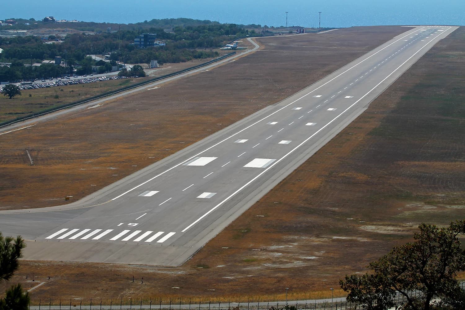 An empty runway with clear markings at Gelendzhik Airport, with the sea visible in the background.