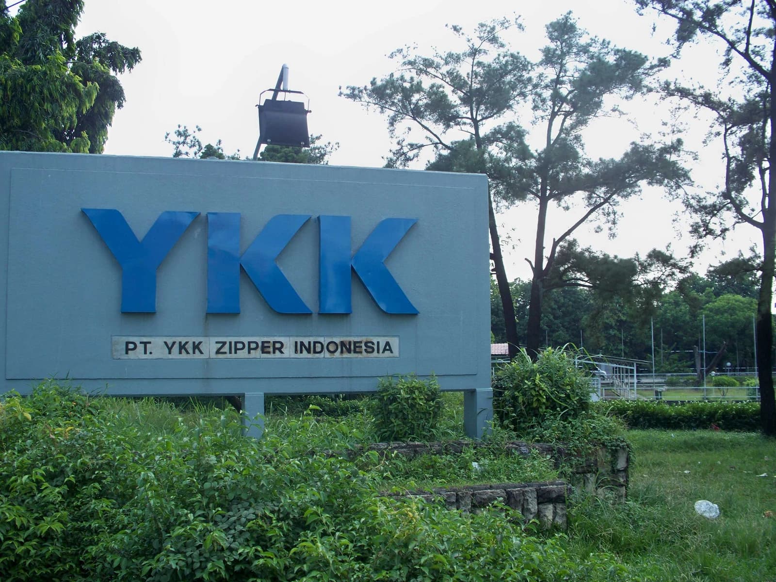 A large sign with the YKK logo and 'PT. YKK Zipper Indonesia' in an outdoor setting.