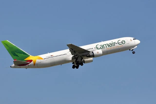 Camair-Co airplane taking off, showing its fuselage, wings, and tail against a blue sky.