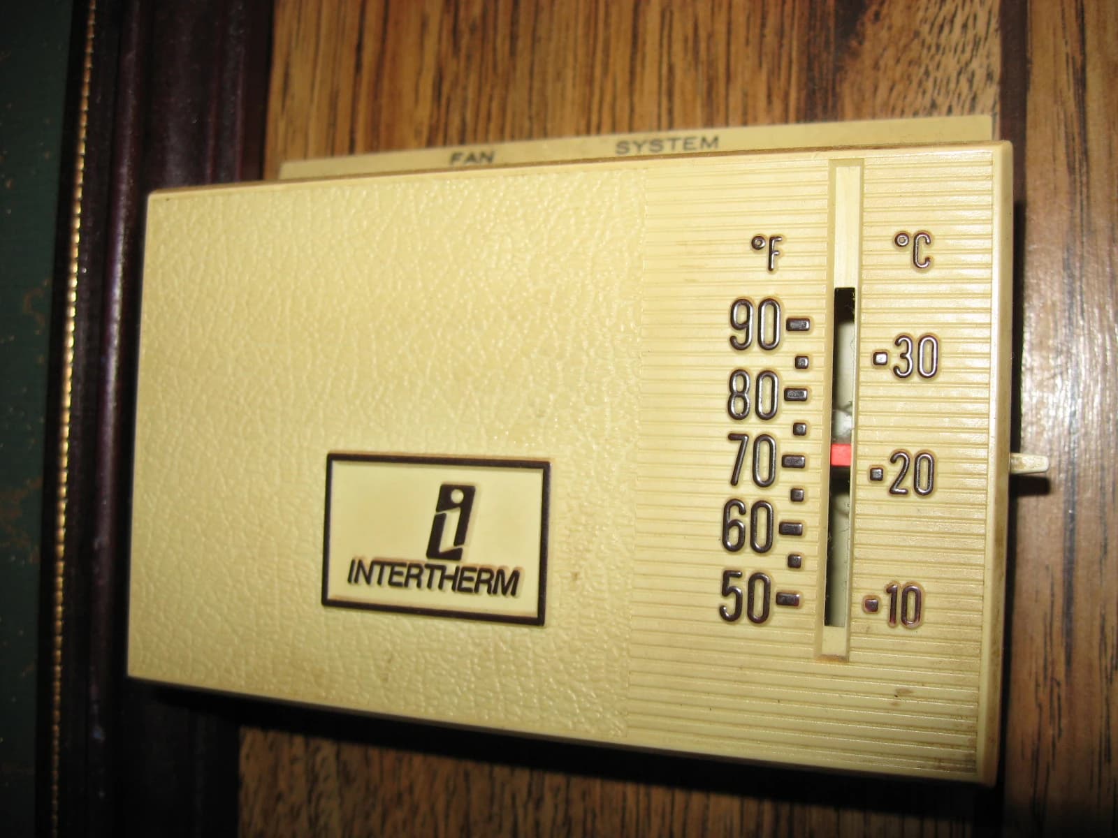 An old Intertherm mechanical thermostat displaying temperature scales in Fahrenheit and Celsius.
