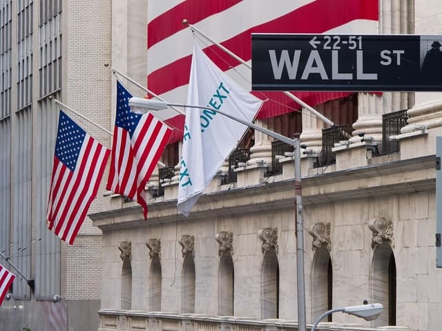 Wall Street sign and multiple American flags displayed outside a building.