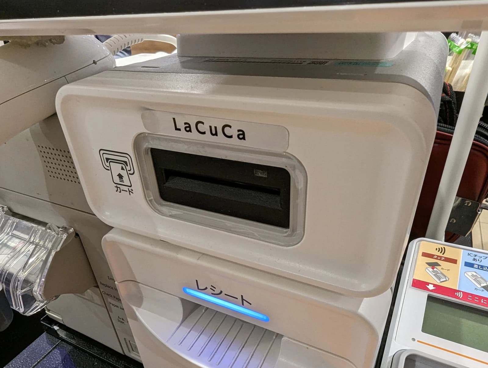 Close-up of a white payment terminal labeled LaCuCa at a supermarket checkout.