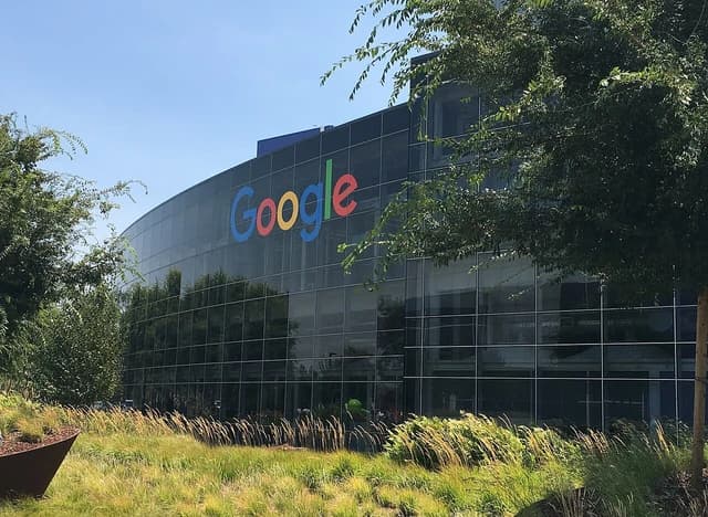 Exterior view of Googleplex headquarters with the Google logo prominently displayed.