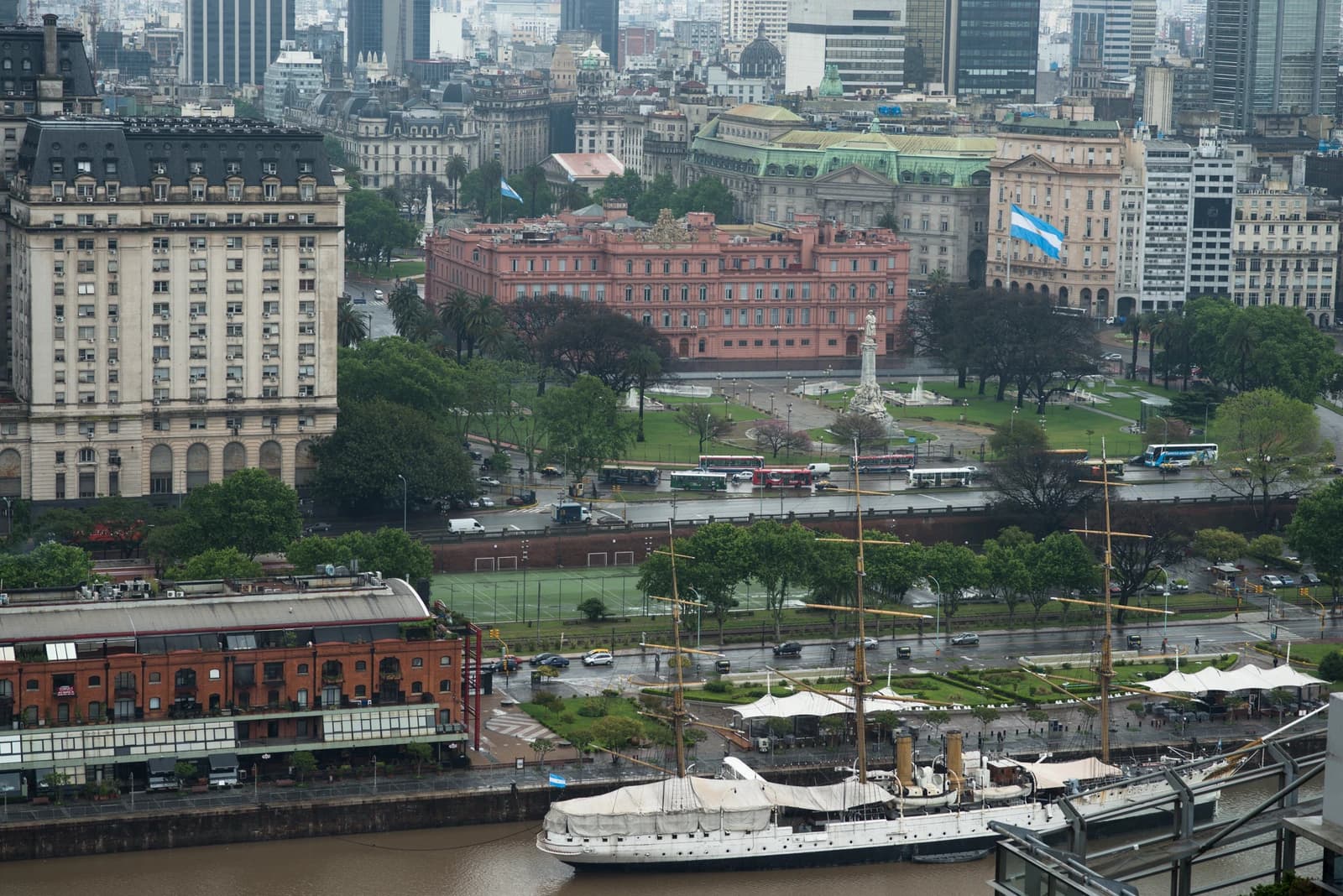 Aerial view of Casa Rosada, the pink presidential palace, overlooking a park and city buildings.