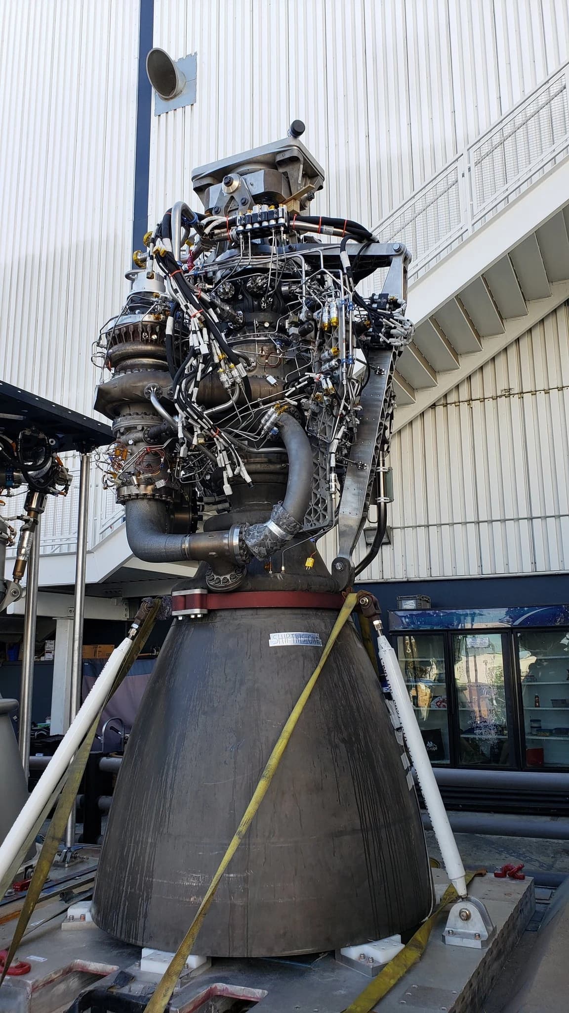 SpaceX Raptor engine, a rocket propulsion system, on display in an industrial setting.