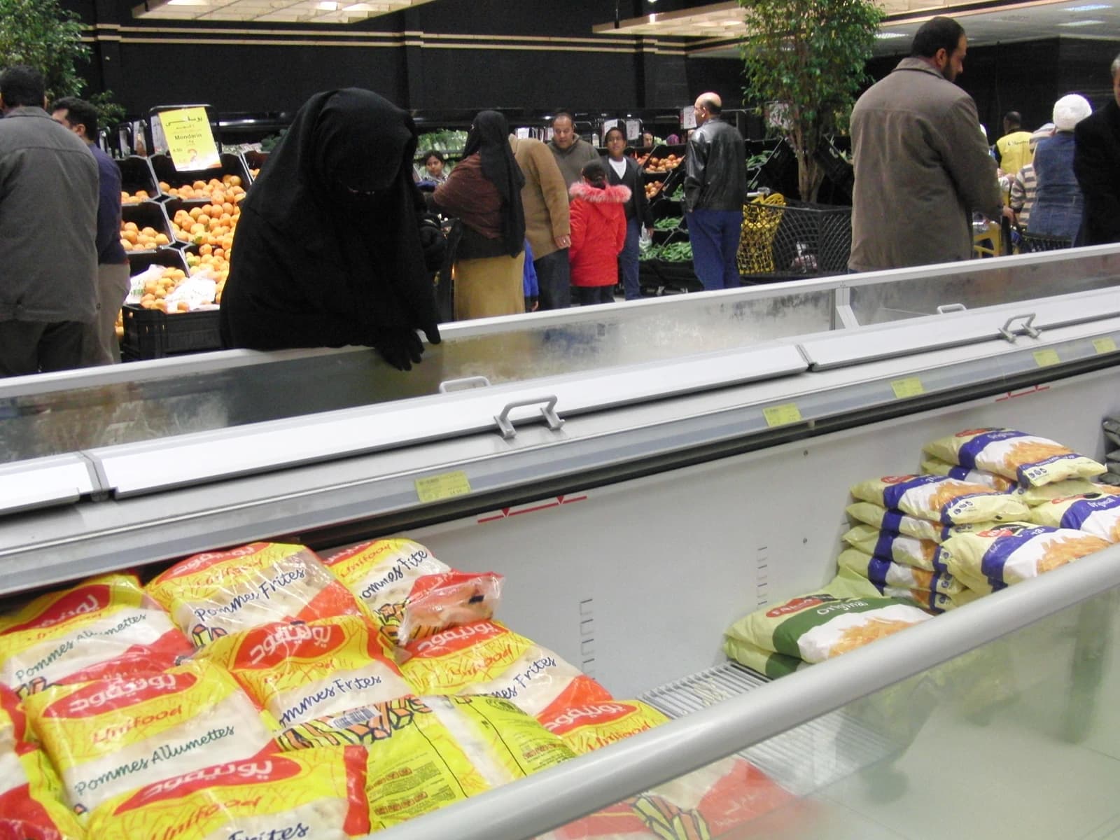 Shoppers look at produce and frozen foods inside a grocery store.