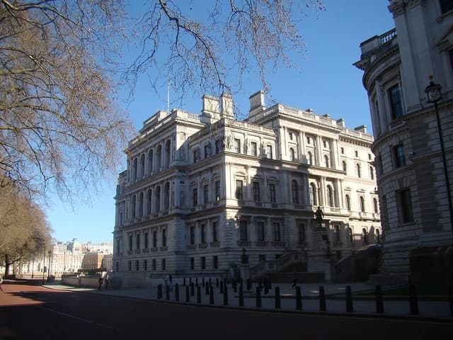 HM Treasury building in London, viewed from Horse Guards Road, under a clear blue sky.