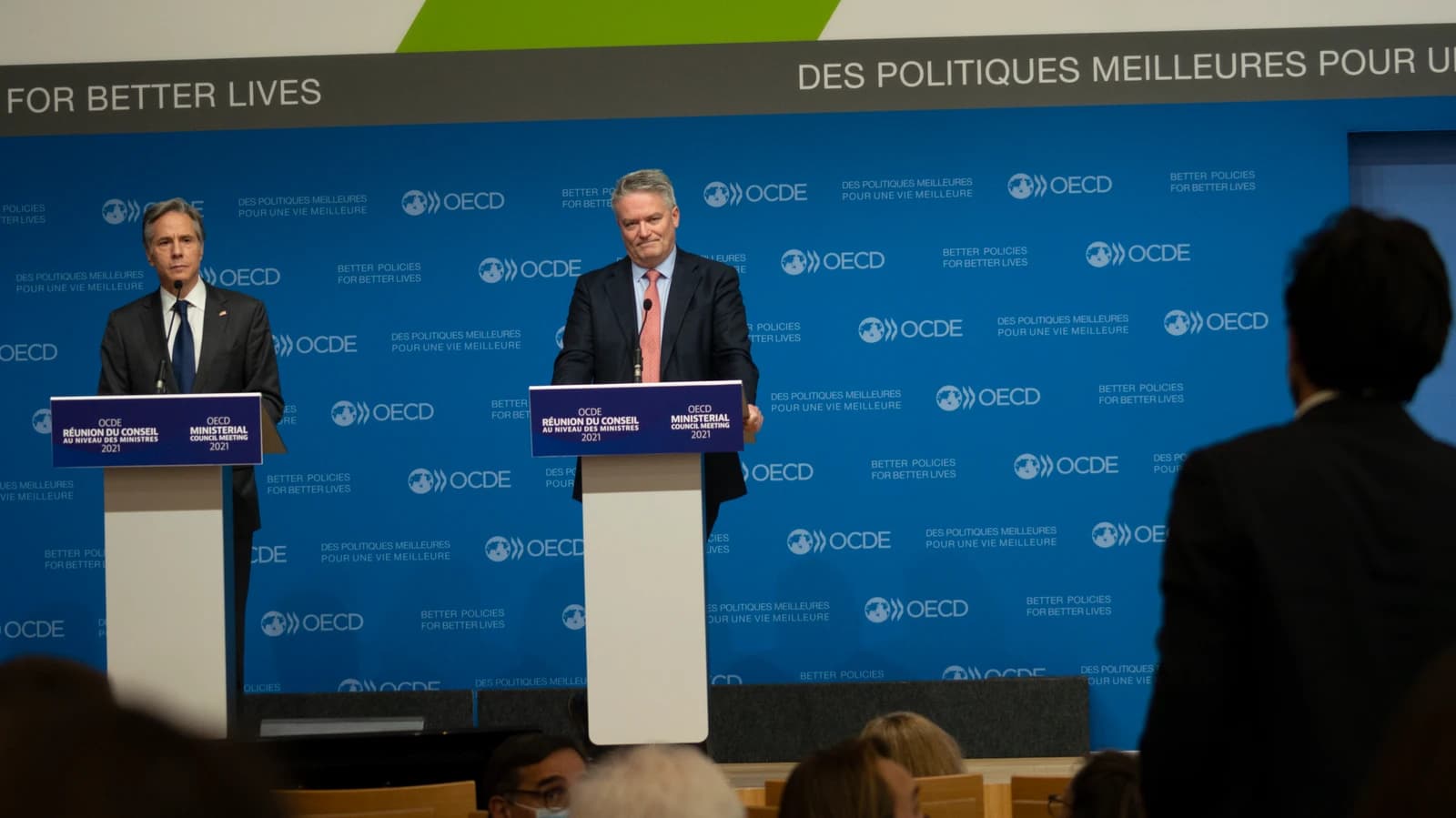 Secretary Blinken and OECD Secretary-General Cormann standing at podiums during a press conference.