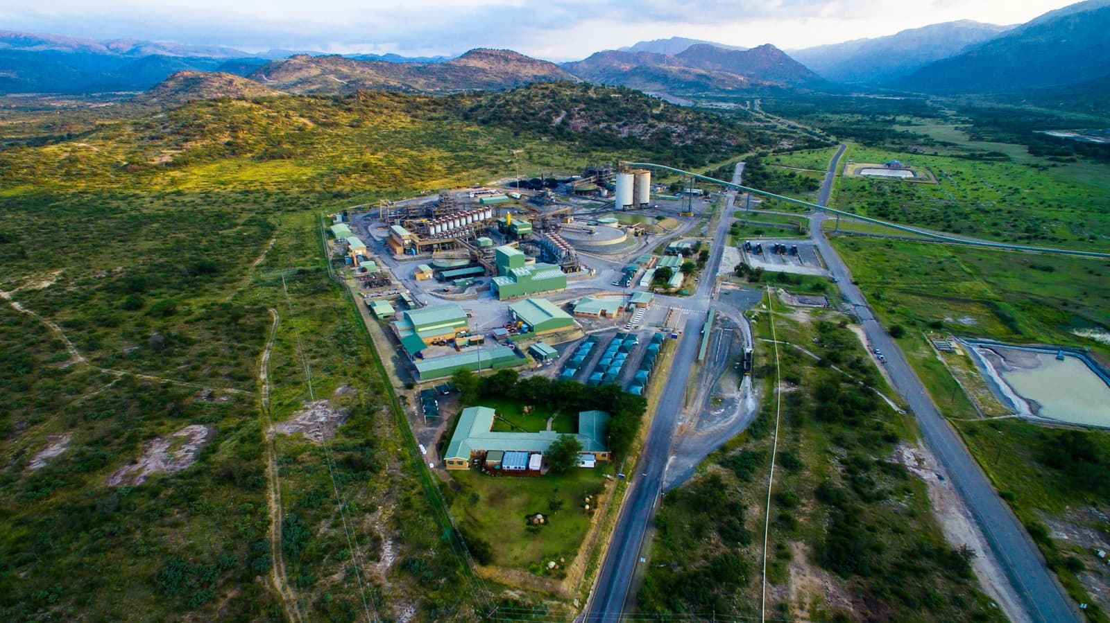Aerial view of a large platinum mining facility with green-roofed buildings and roads.