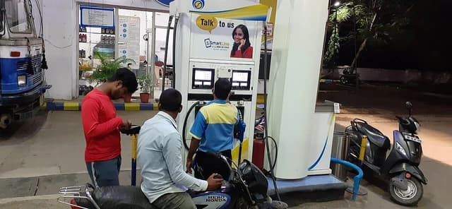 People fill up vehicles at a Bharat Petroleum petrol pump at night.