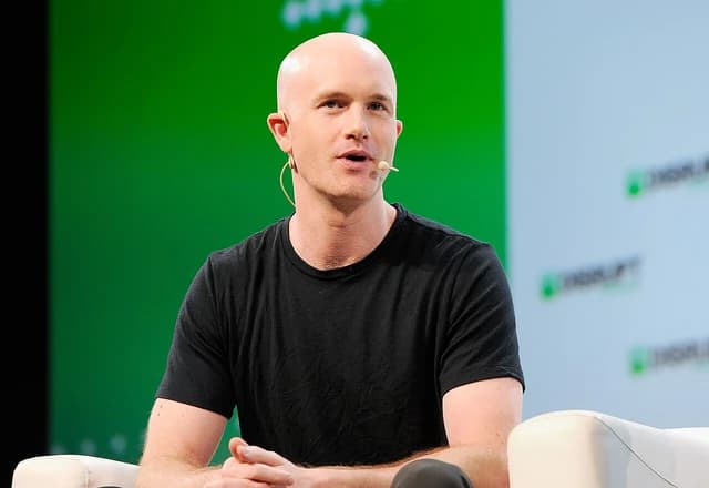 Brian Armstrong, CEO of Coinbase, speaking into a microphone on stage.