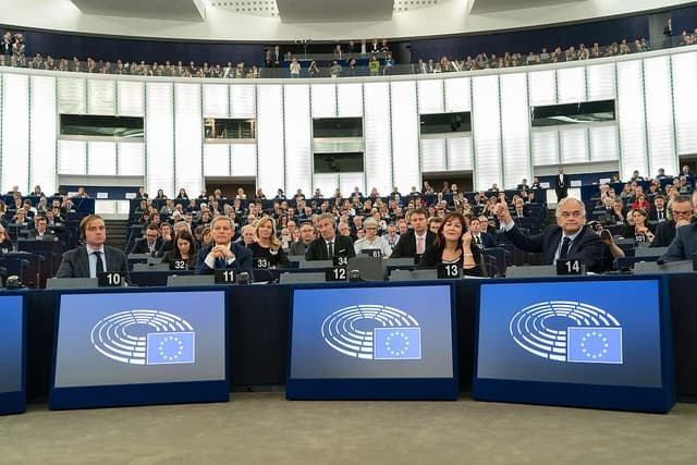Members of the European Parliament seated in a plenary session chamber.