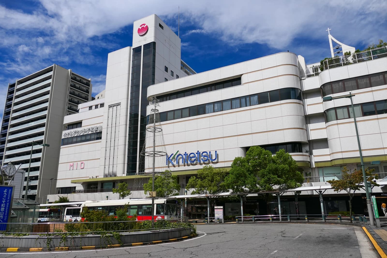 Kintetsu Department Store building in Wakayama, Japan with bus stop in front.