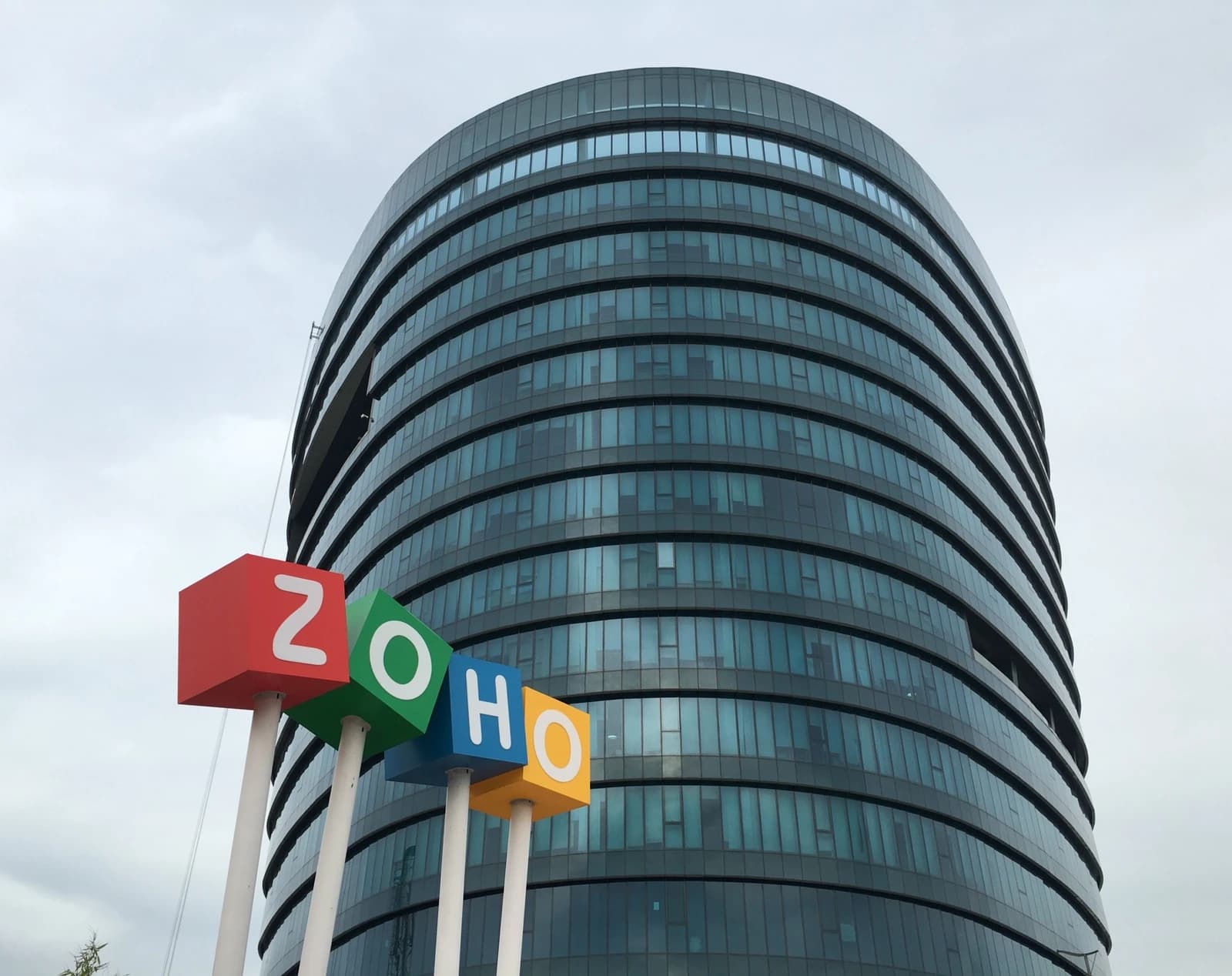 Zoho headquarters building with large, colorful 'ZOHO' signage in front.