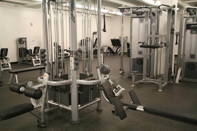 Multifunctional cable and row machines in an empty gym interior.