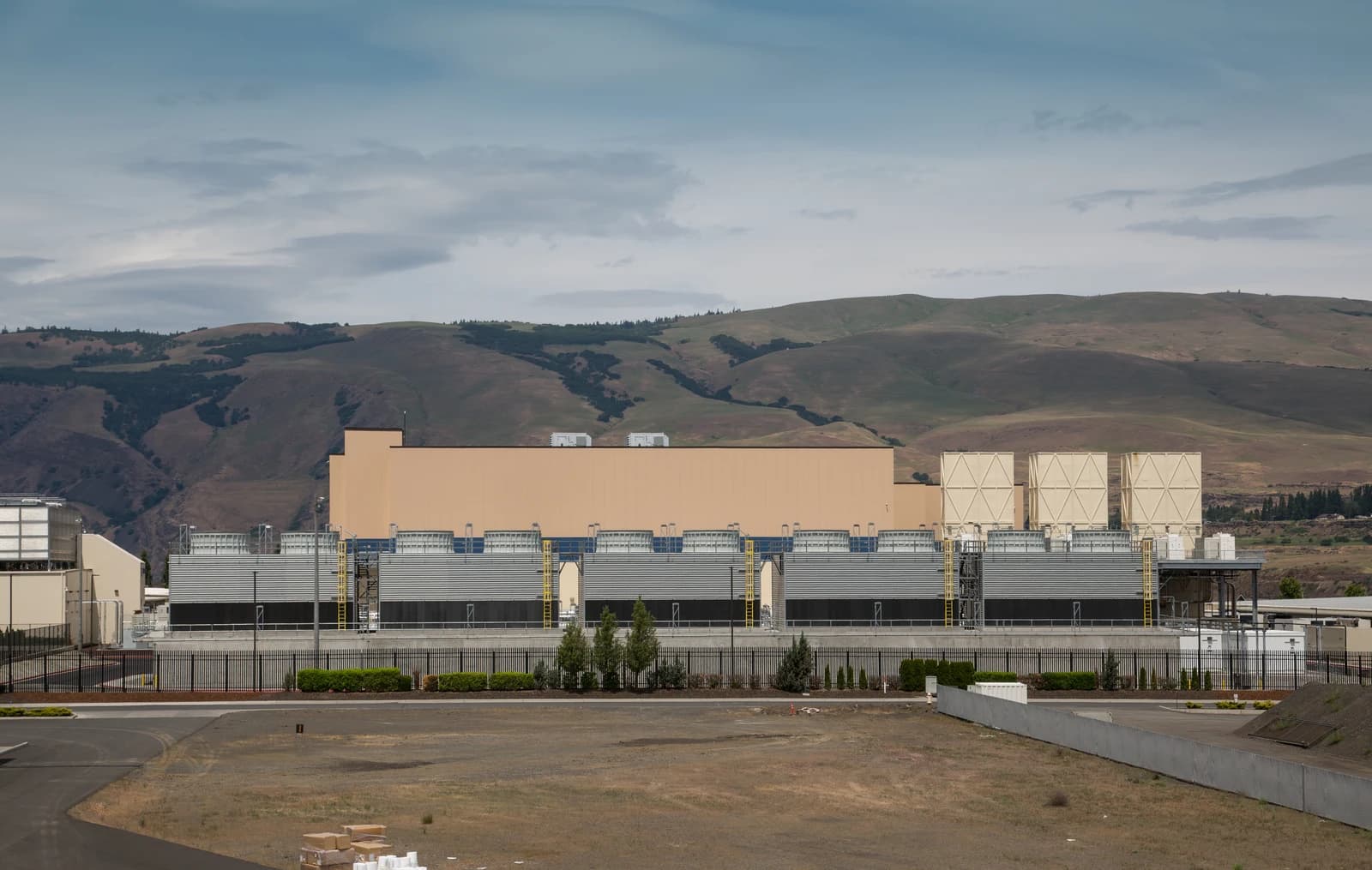 Exterior view of a large Google data center building in The Dalles, Oregon, with hills in the background.
