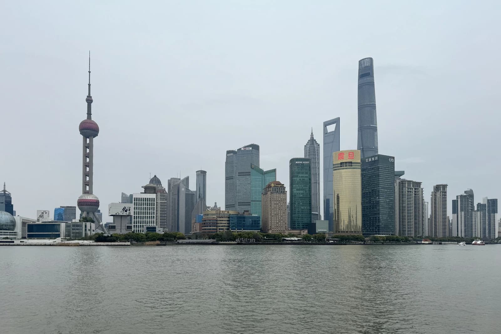 Shanghai skyline featuring the Oriental Pearl TV Tower and many tall buildings along the river.
